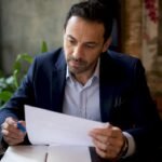 Un imprenditore controlla la lista di conformità ISO alla scrivania del suo ufficio.