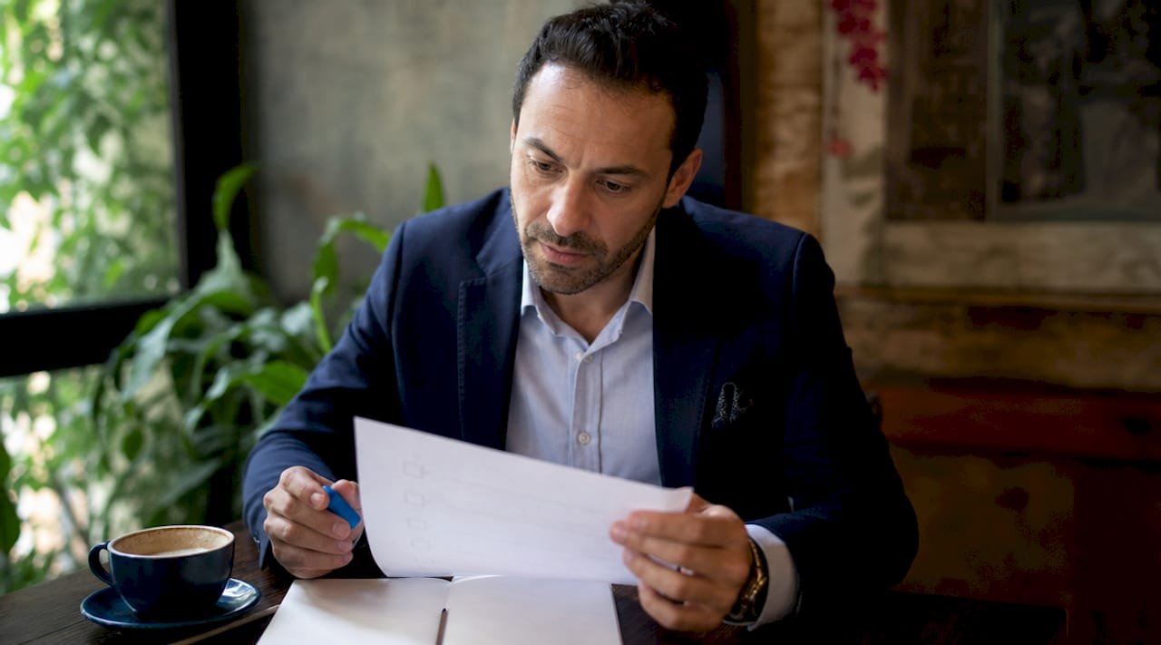 Un imprenditore controlla la lista di conformità ISO alla scrivania del suo ufficio.
