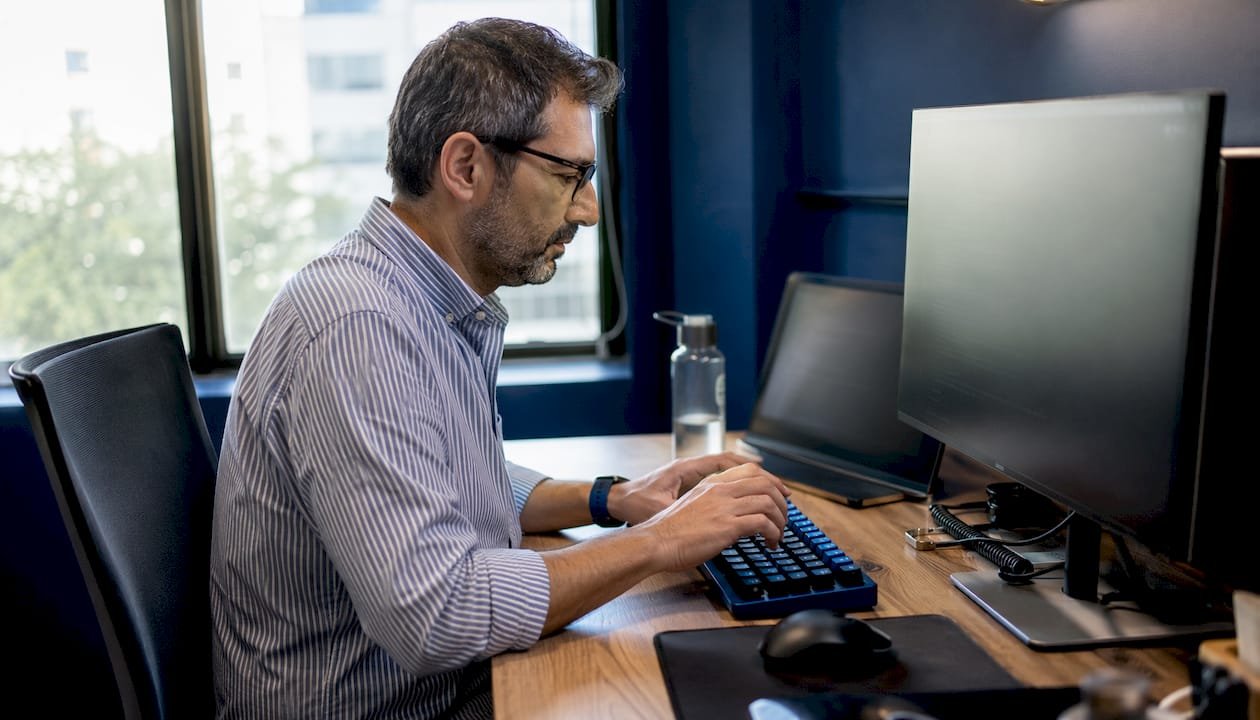 Un programmatore lavora al computer scrivendo codice nel suo ufficio.