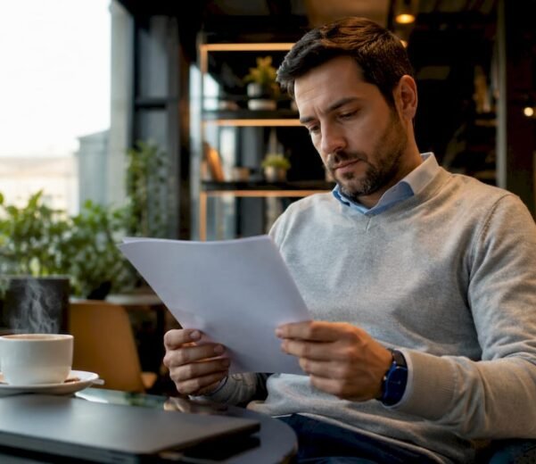 Un esperto informatico alle prese con la lettura di un documento ISO nel suo ufficio.