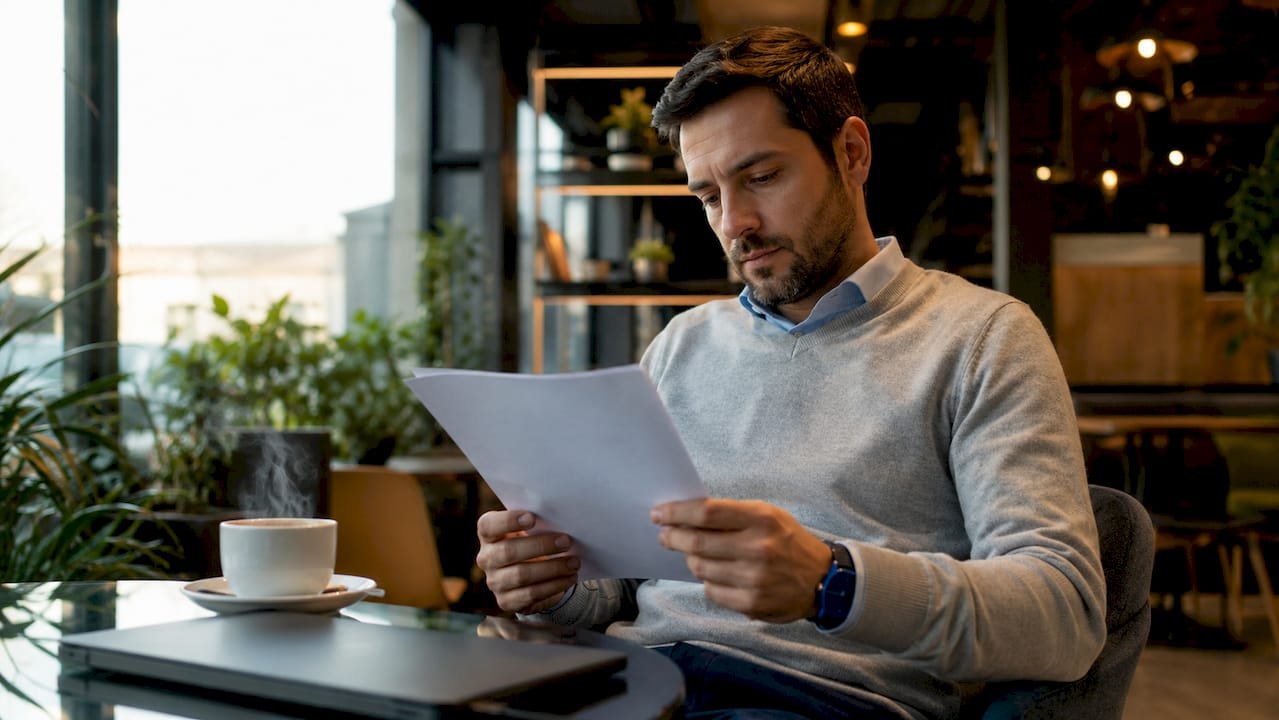 Un esperto informatico alle prese con la lettura di un documento ISO nel suo ufficio.