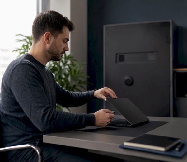 Mani che tengono un token di sicurezza accanto a un laptop