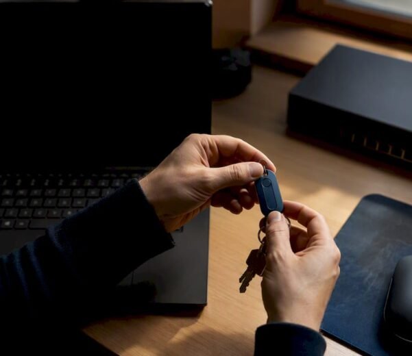 Mani che tengono un token di sicurezza posato su una scrivania in un ufficio IT