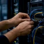 Mani di un tecnico all'opera mentre collega i cavi all'interno di un data center