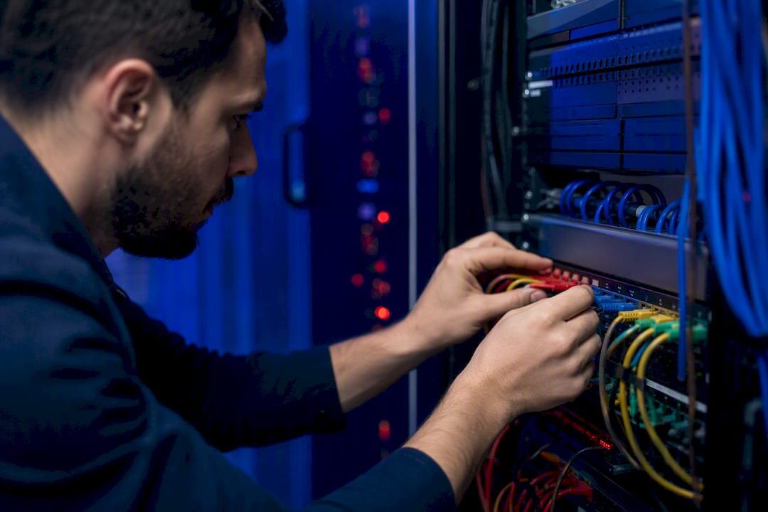 Mani che gestiscono i cavi di rete nella sala server