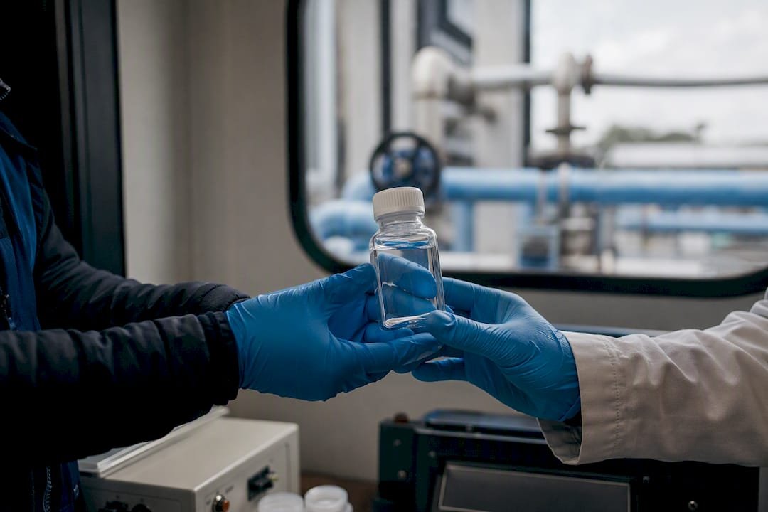 Mani che scambiano un campione d'acqua durante un audit ambientale